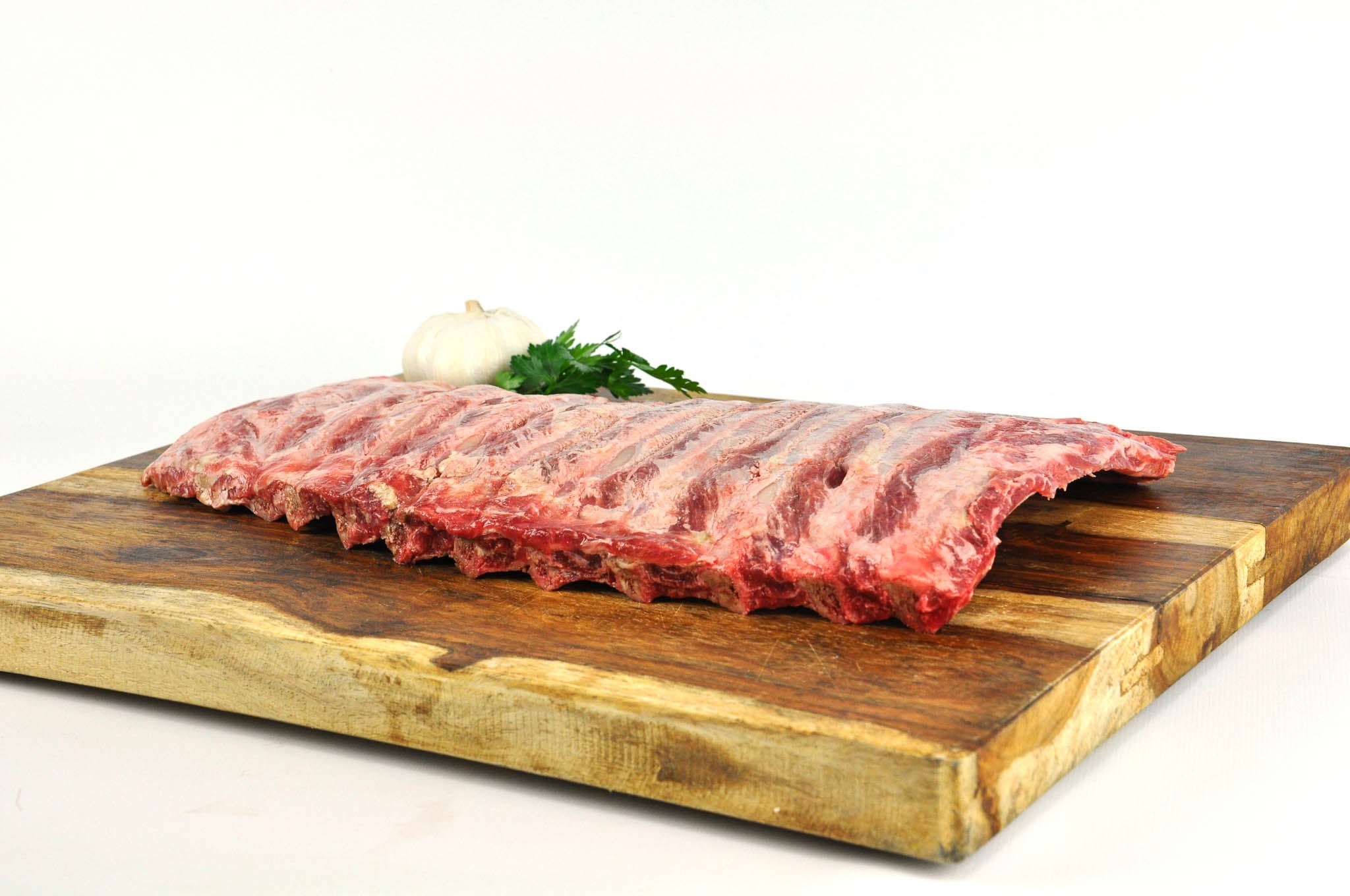 Raw ribs on a wooden cutting board with a white background