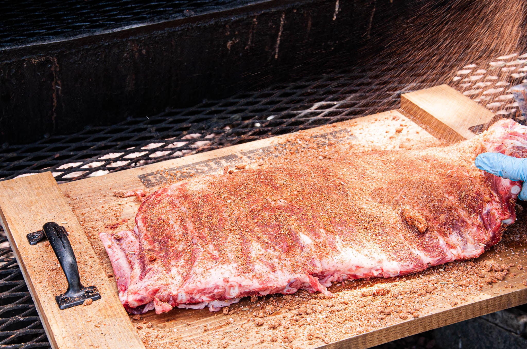 Raw ribs on a wooden cutting board over a grill