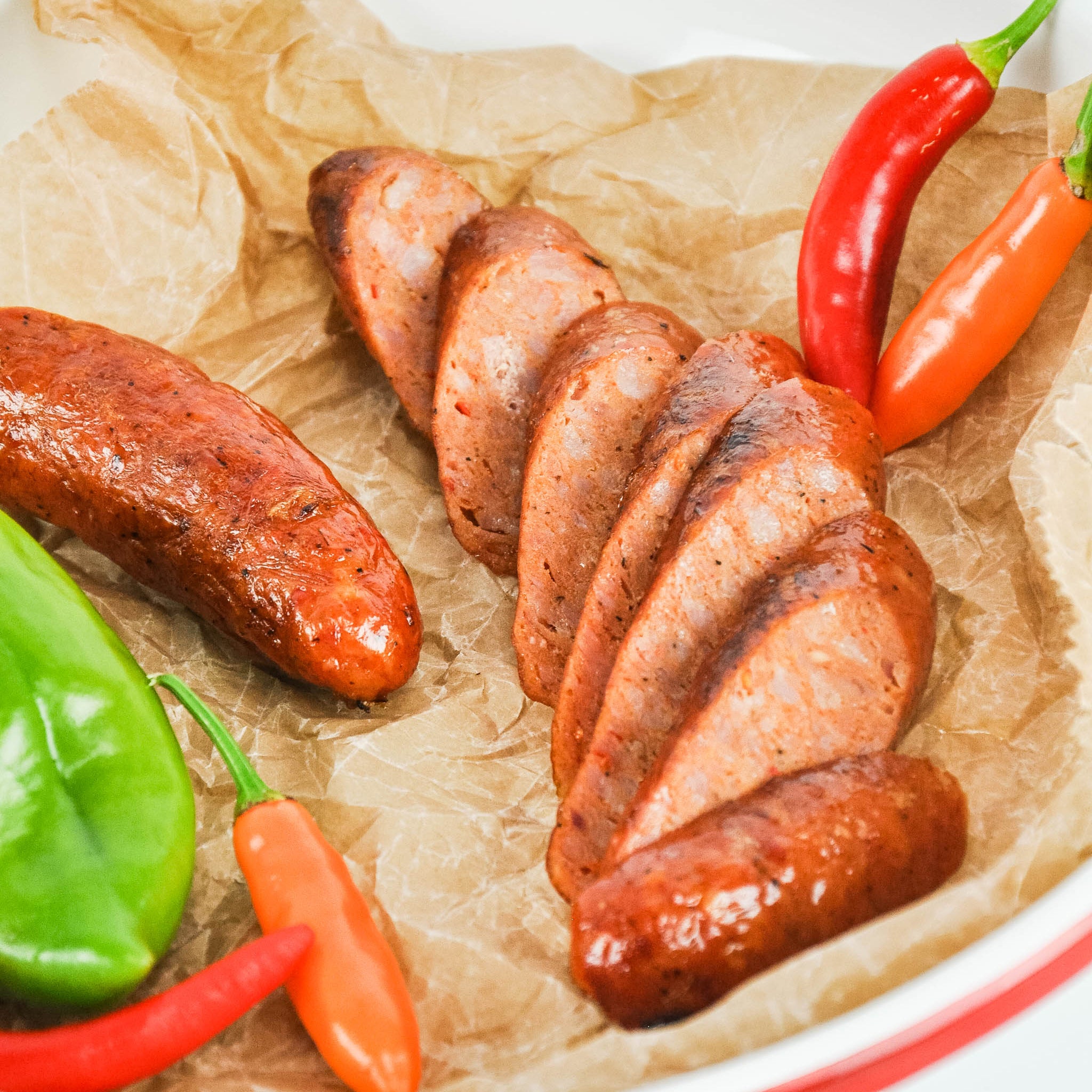 Sliced sausages with red and green peppers on brown paper