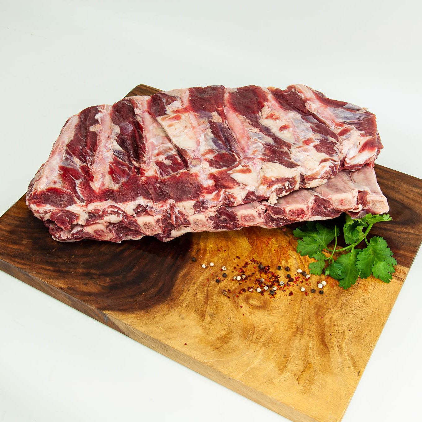 Raw ribs on a wooden cutting board with herbs and spices