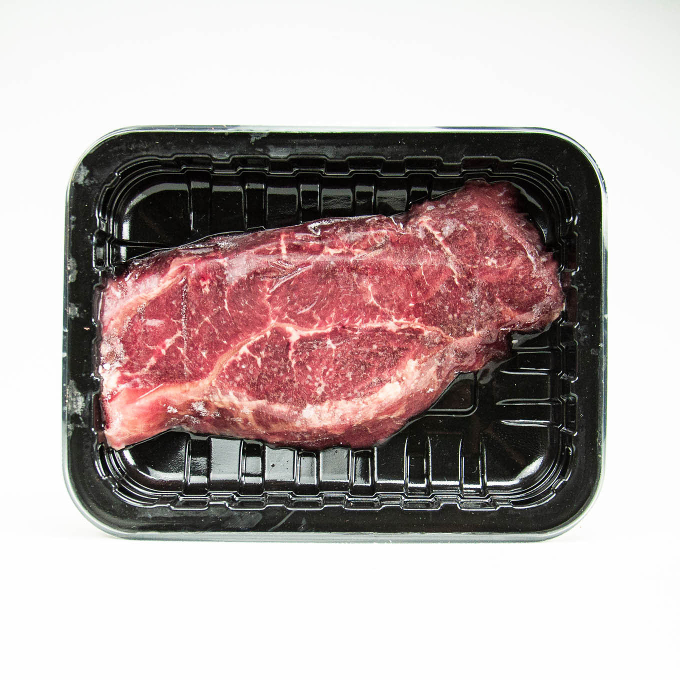 Raw steak in a black plastic container on a white background
