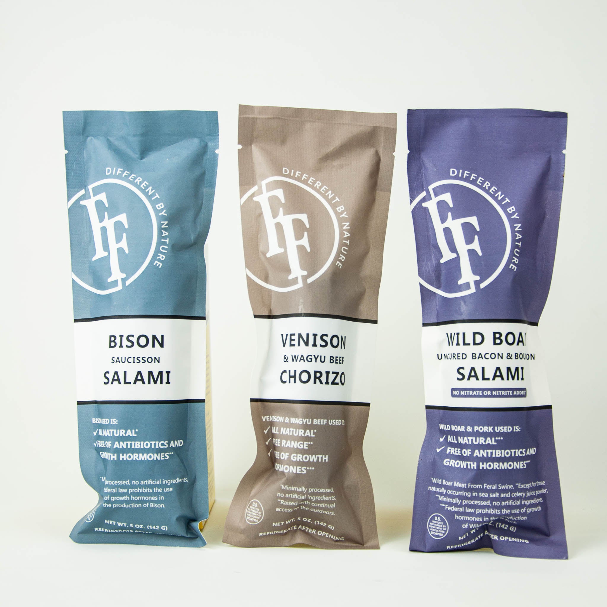 Three packages of different types of salami with visible branding on a white background