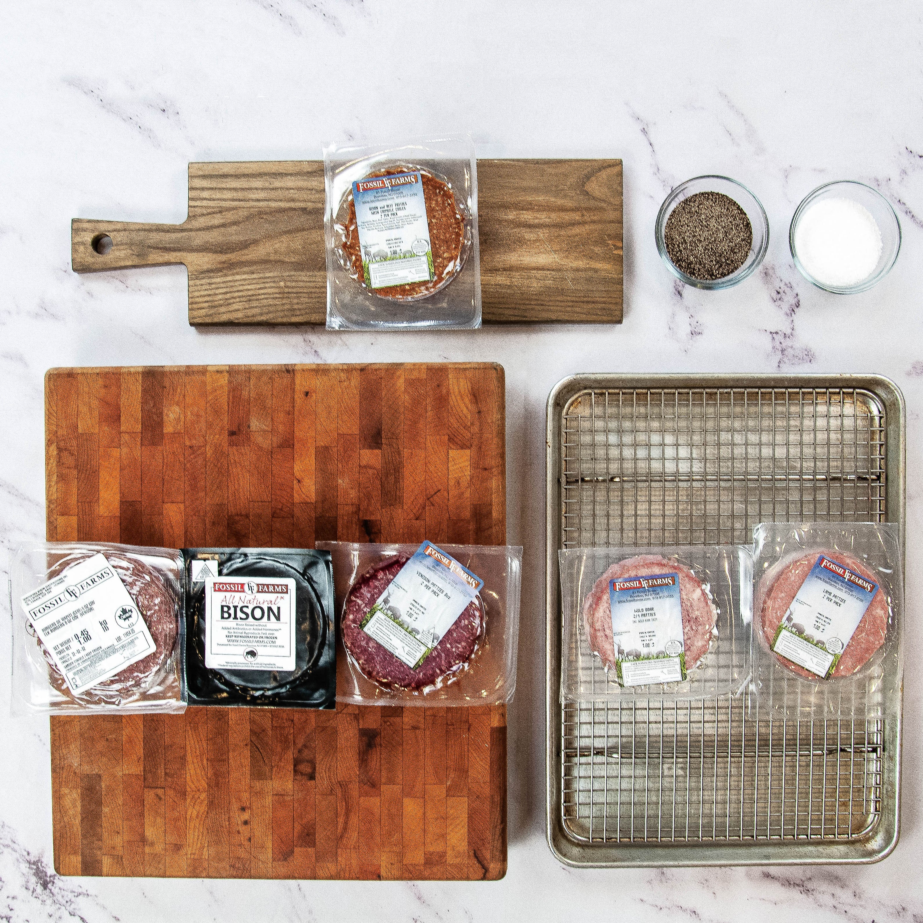 Assorted packaged meats on a marble surface with cutting boards and a tray.