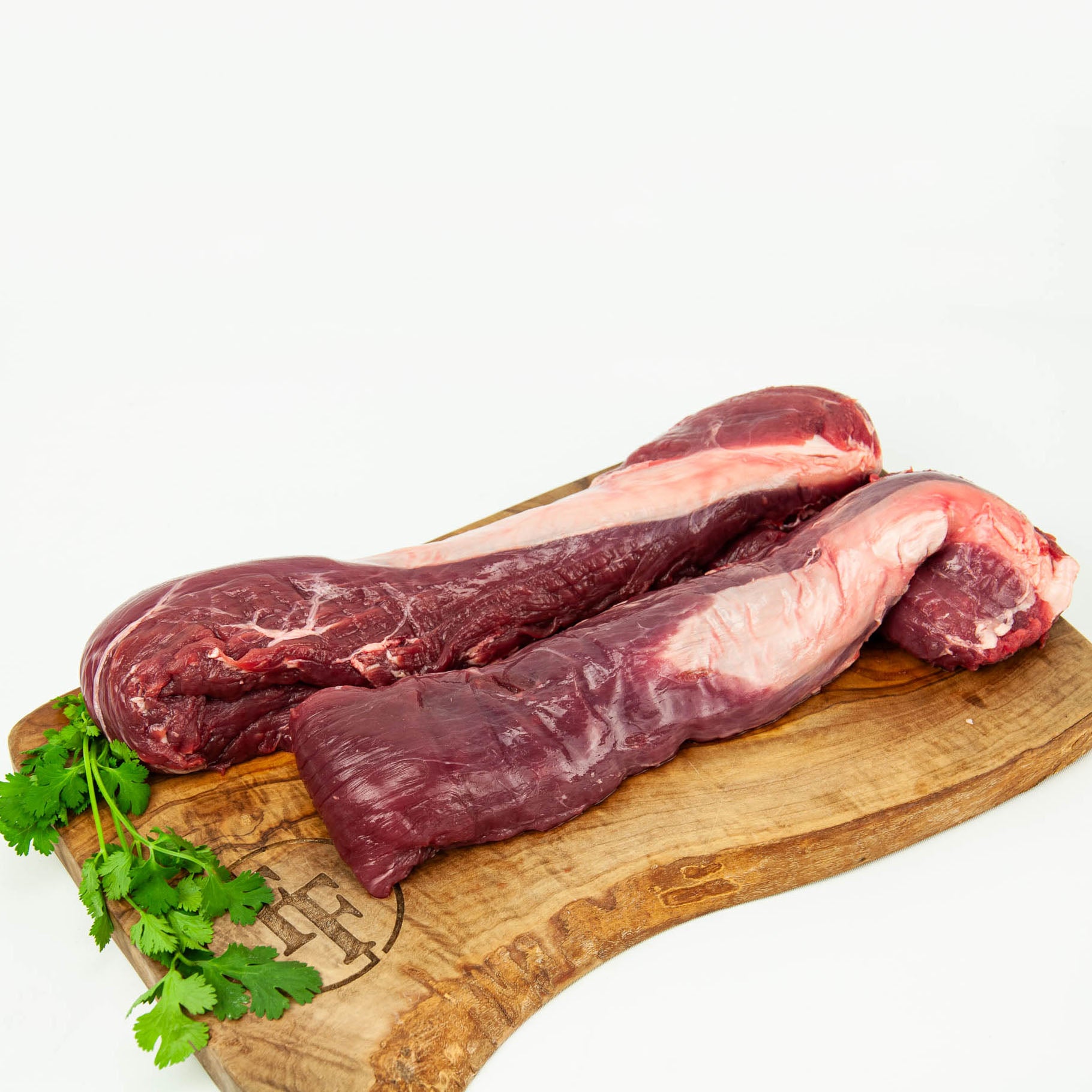 Raw meat on a wooden cutting board with parsley on a white background