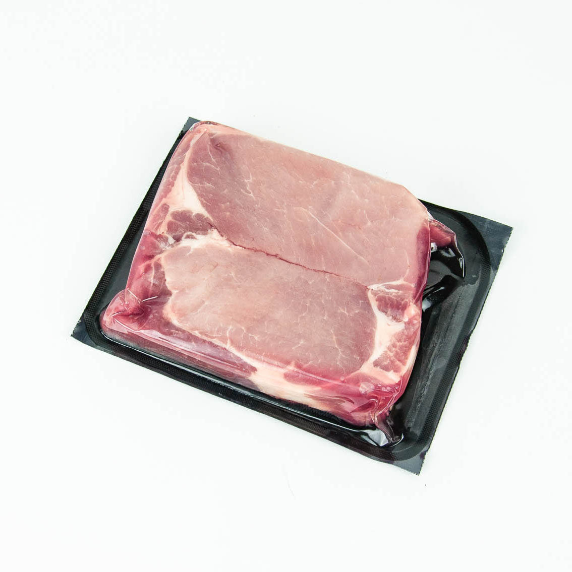 Raw pork chop in a black plastic packaging on a white background