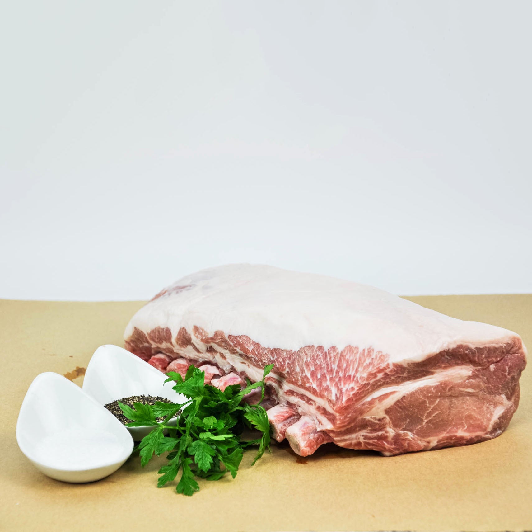 Raw pork belly with herbs and salt on a wooden surface