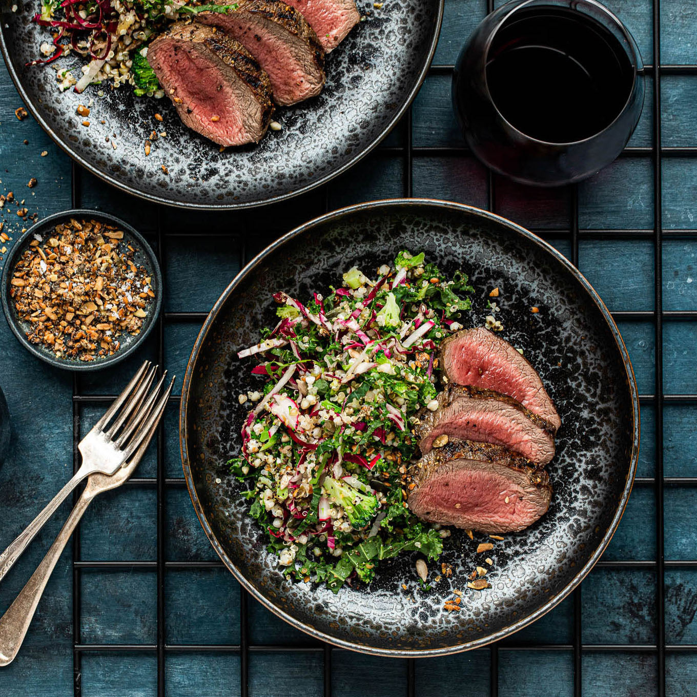 Plated dish of sliced beef with a side salad on a textured surface.