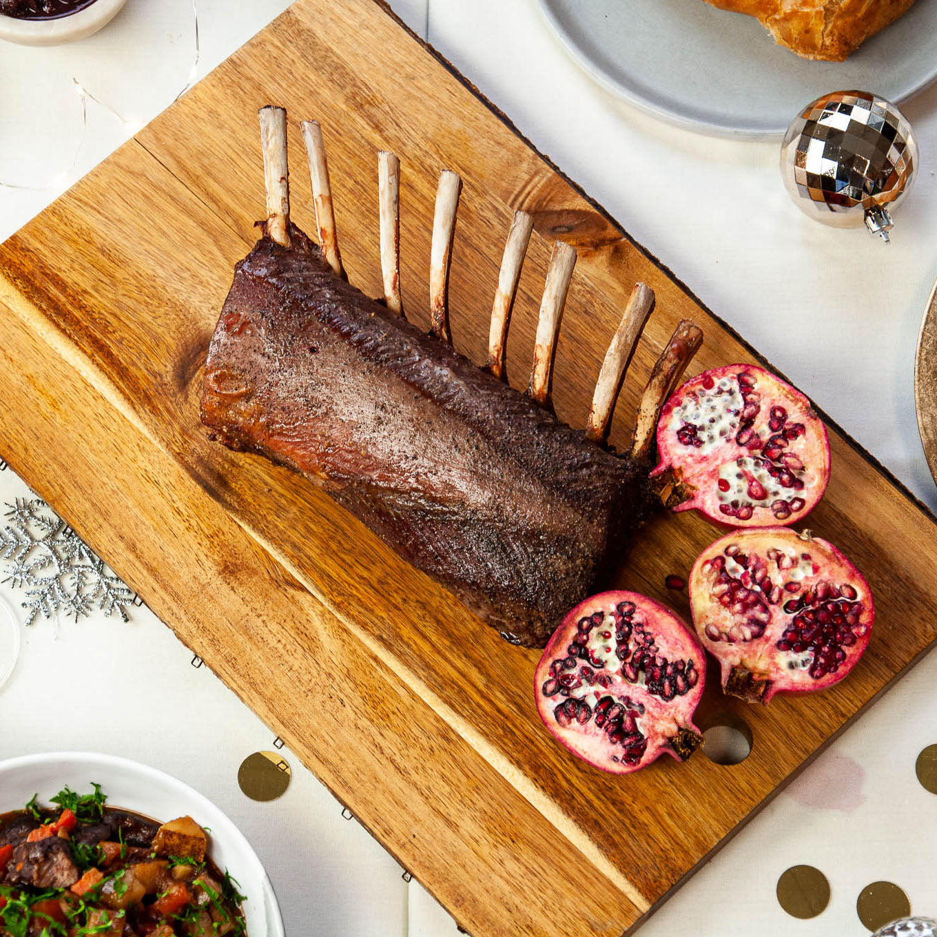 Roasted rack of lamb with pomegranate on a wooden cutting board