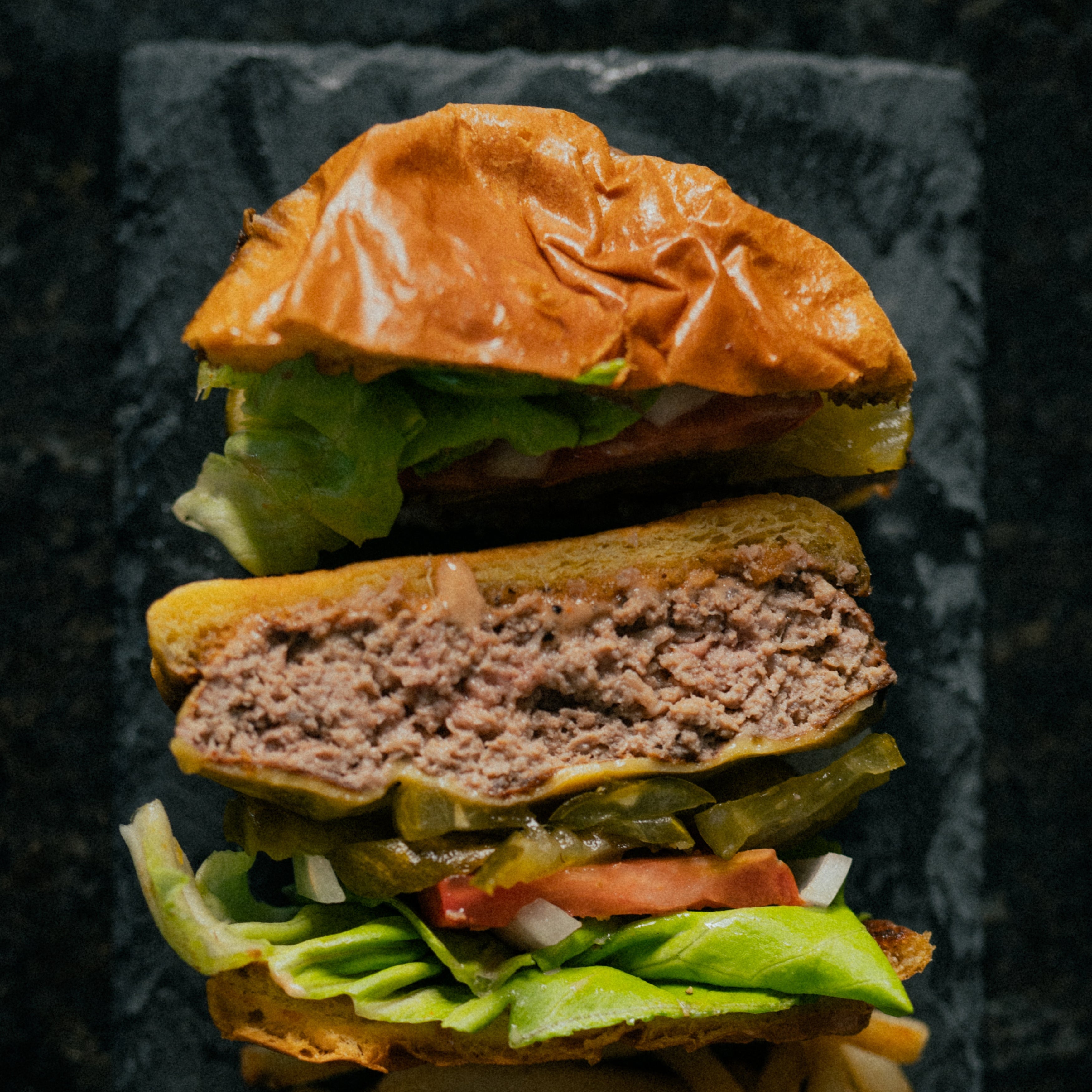 Hamburger and French fries on a dark slate surface