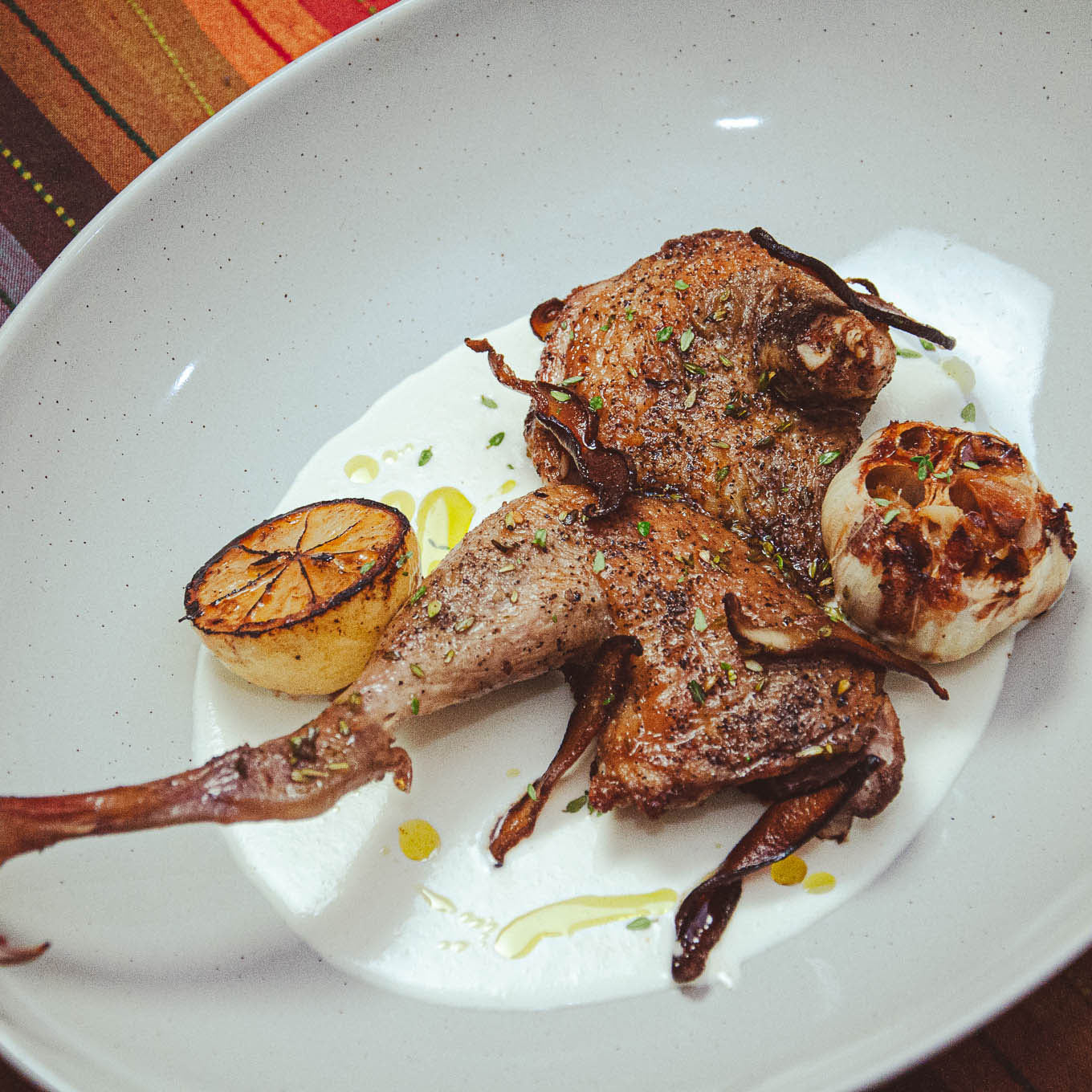 Roasted guinea hen with garlic and lemon on a white plate