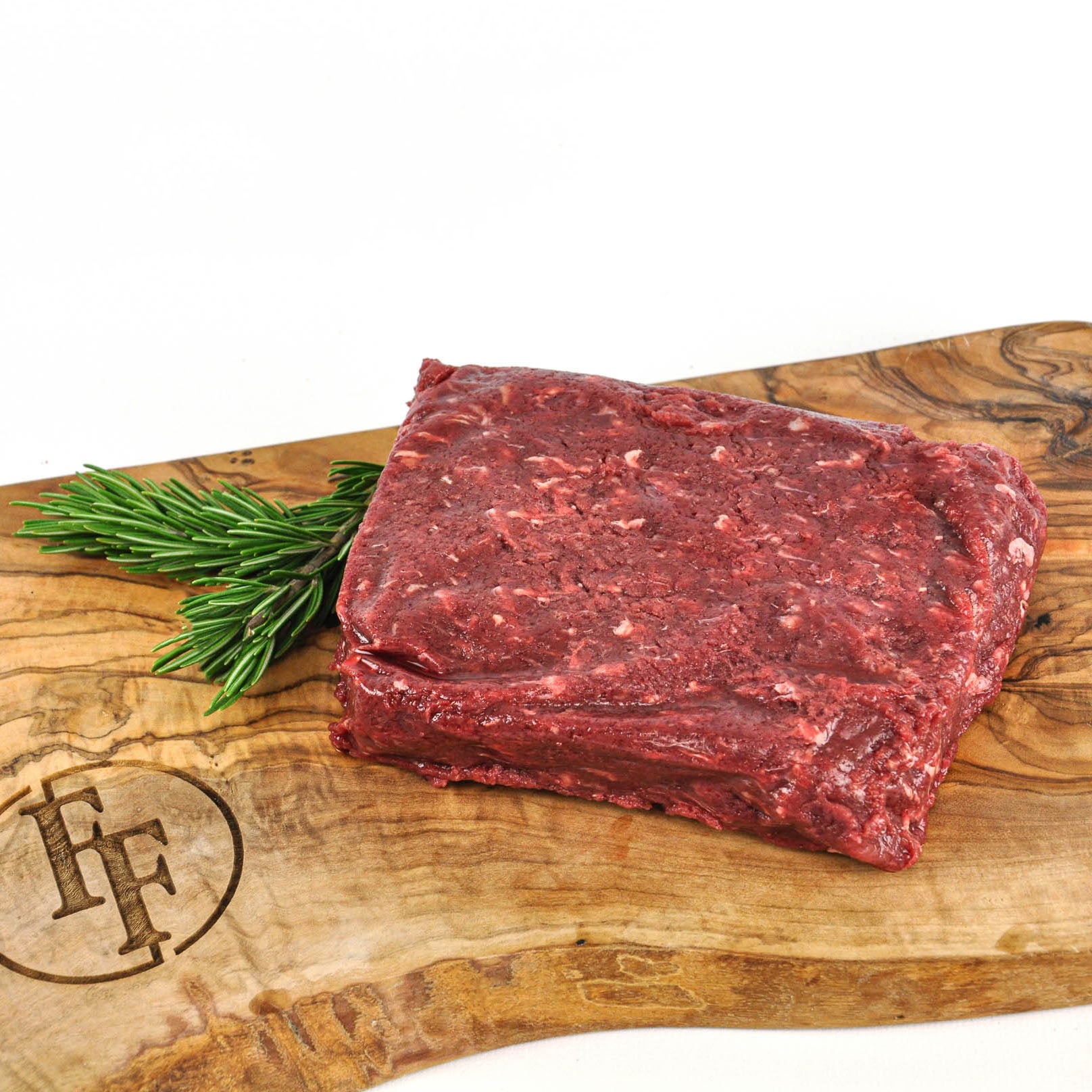 Raw beef on a wooden cutting board with rosemary, featuring a brand logo.