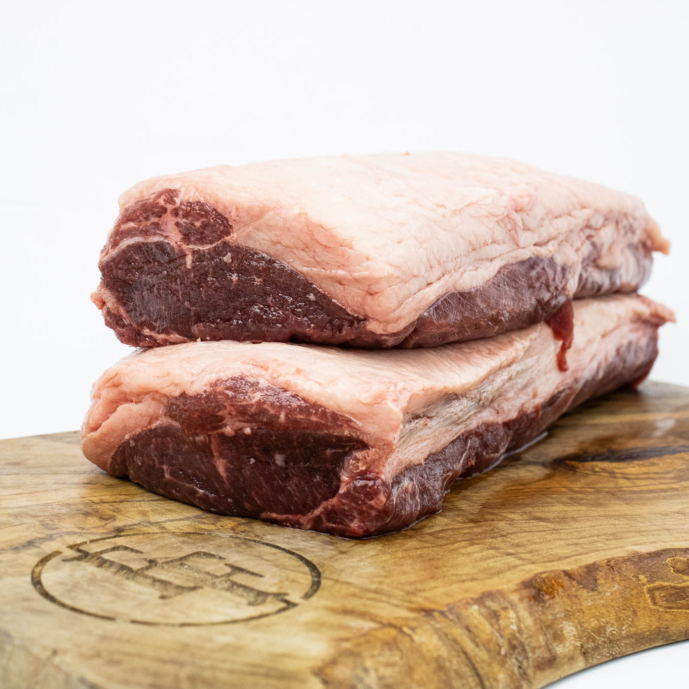 Two pieces of raw meat on a wooden cutting board with a white background