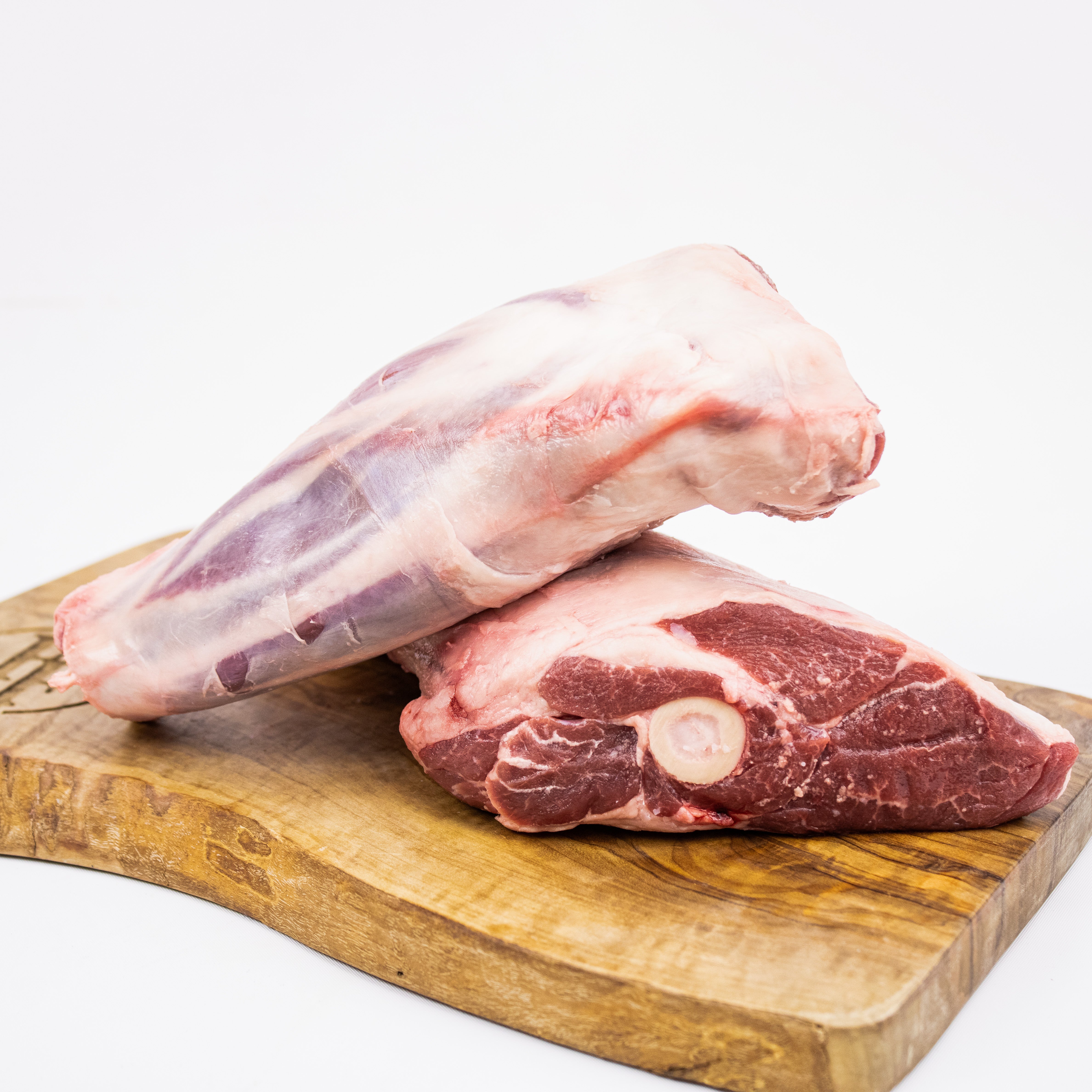 Two pieces of raw meat on a wooden cutting board with a white background