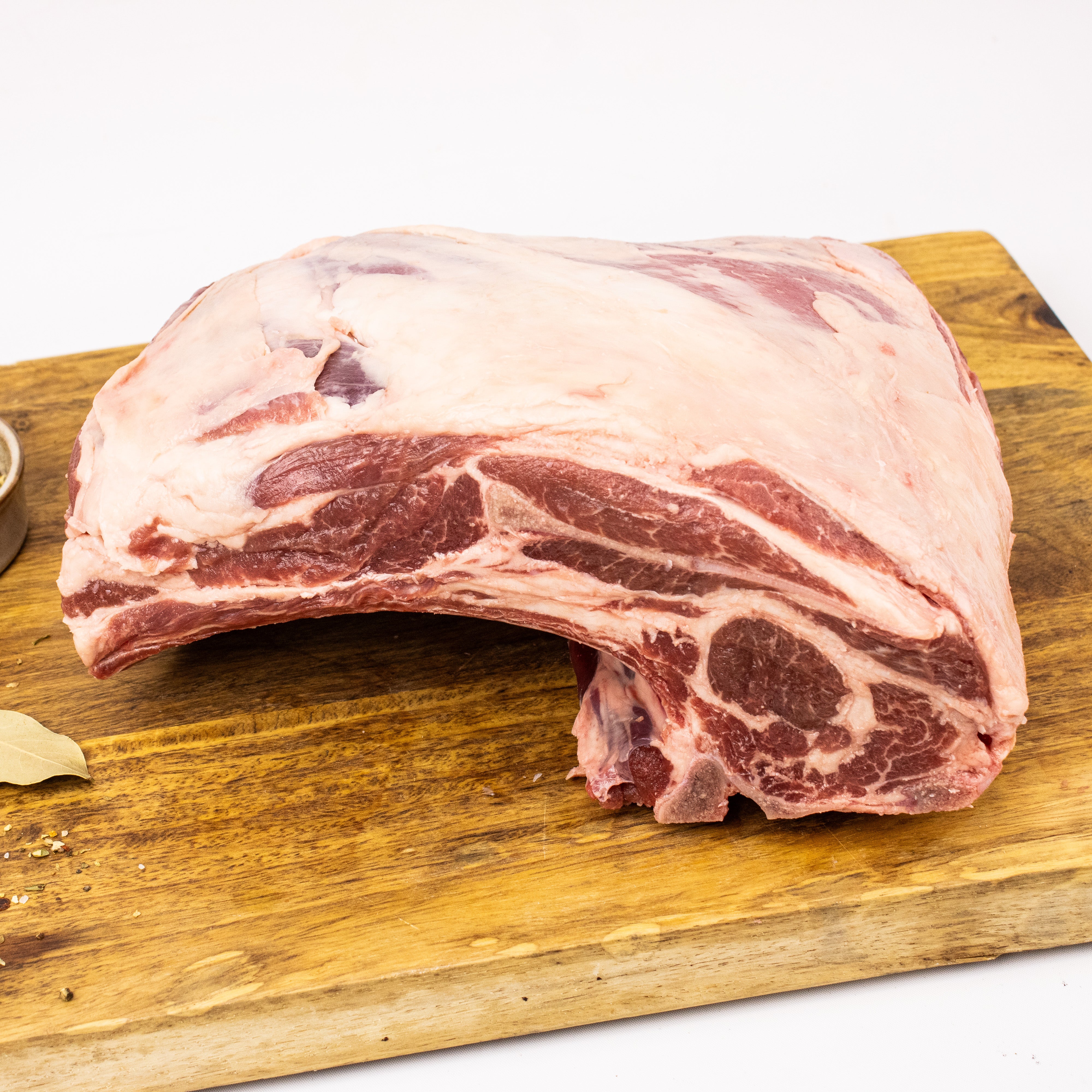 Raw rib of beef on a wooden cutting board with a white background