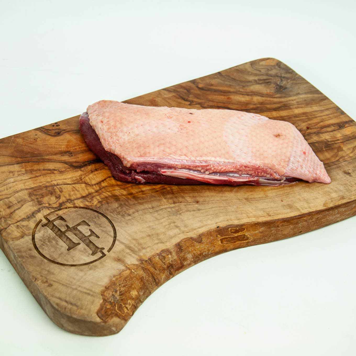 Raw meat on a wooden cutting board with a brand logo.