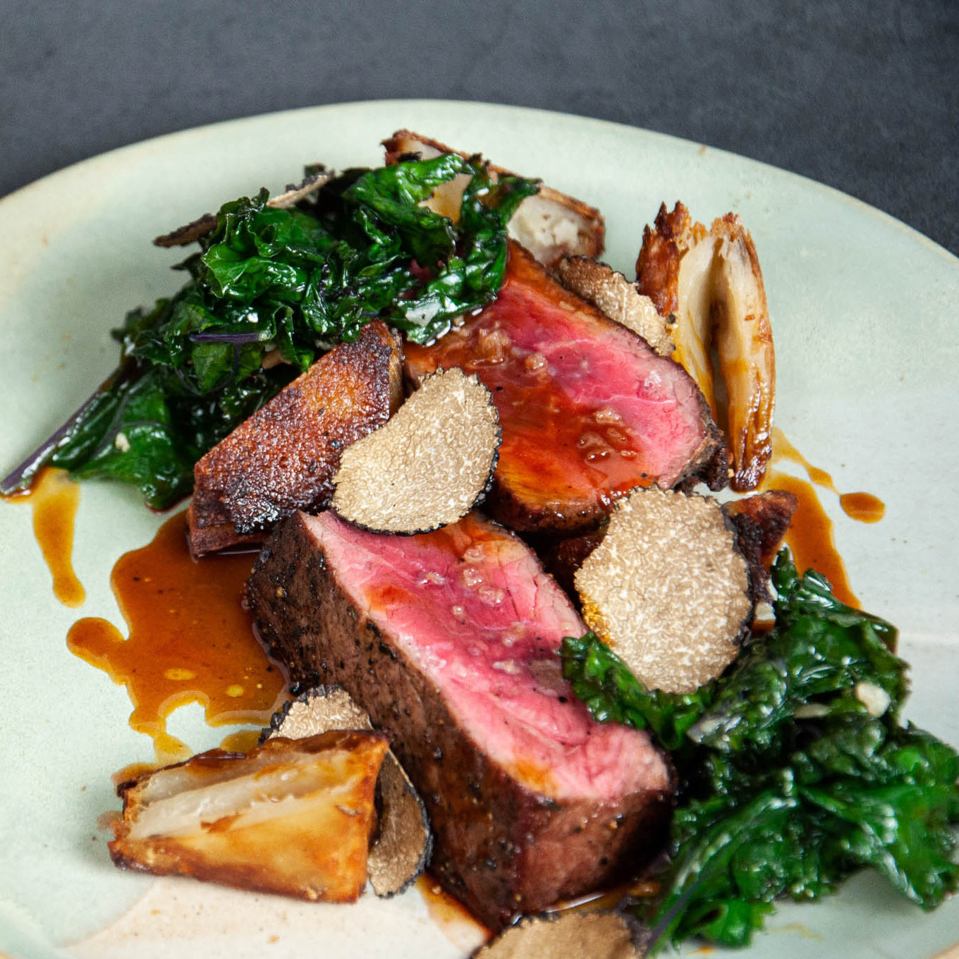 Plated dish with sliced beef, greens, and garnishes on a white plate.