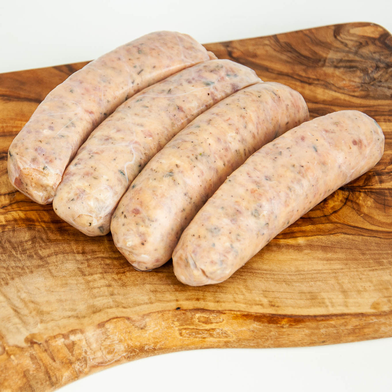Four raw sausages on a wooden cutting board