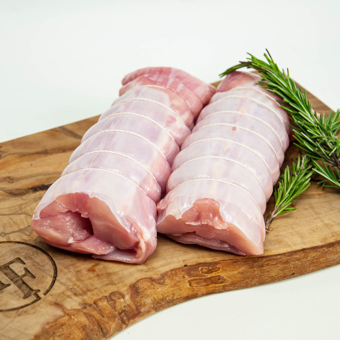 Raw pork belly slices on a wooden cutting board with rosemary