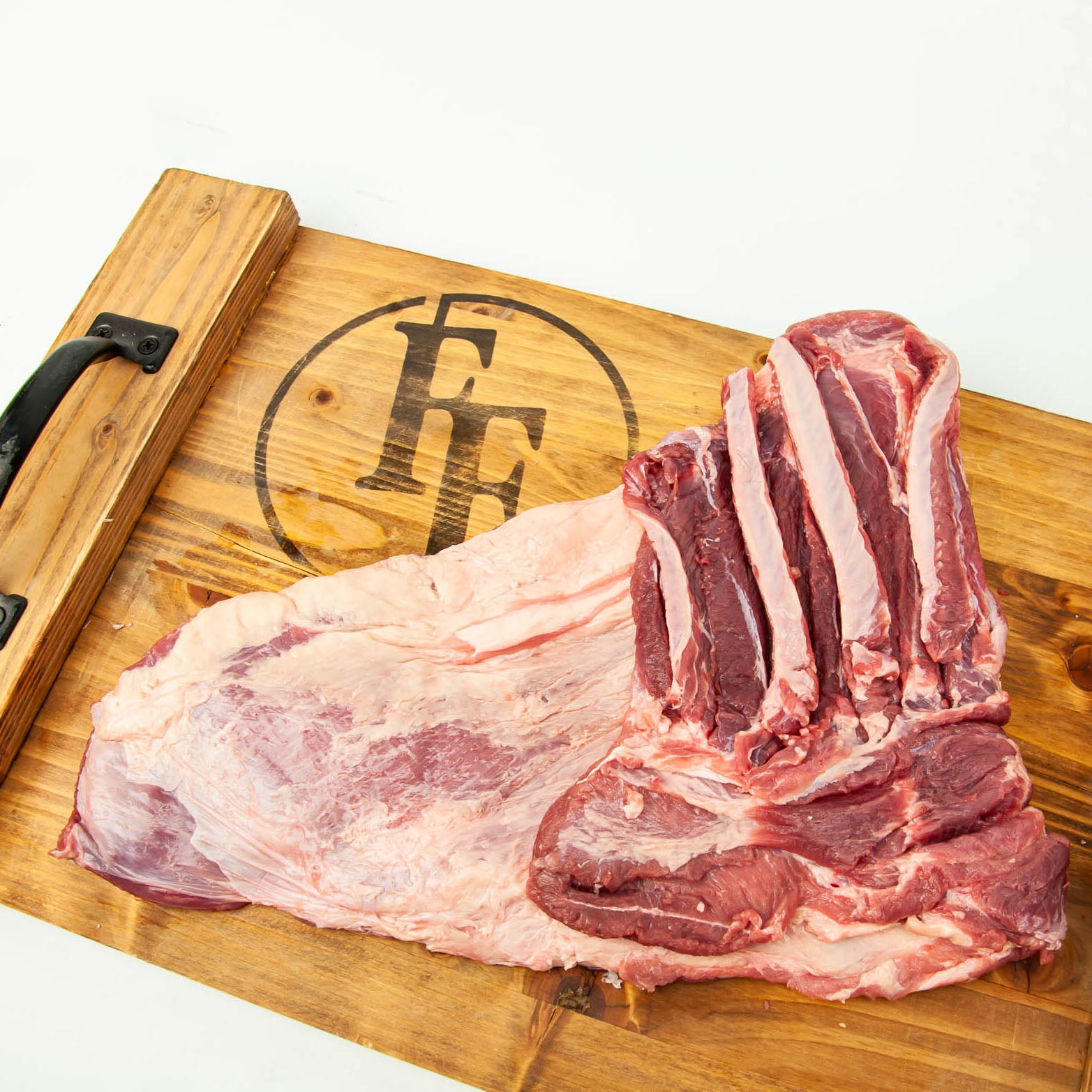 Raw meat on a wooden cutting board with a visible brand logo.