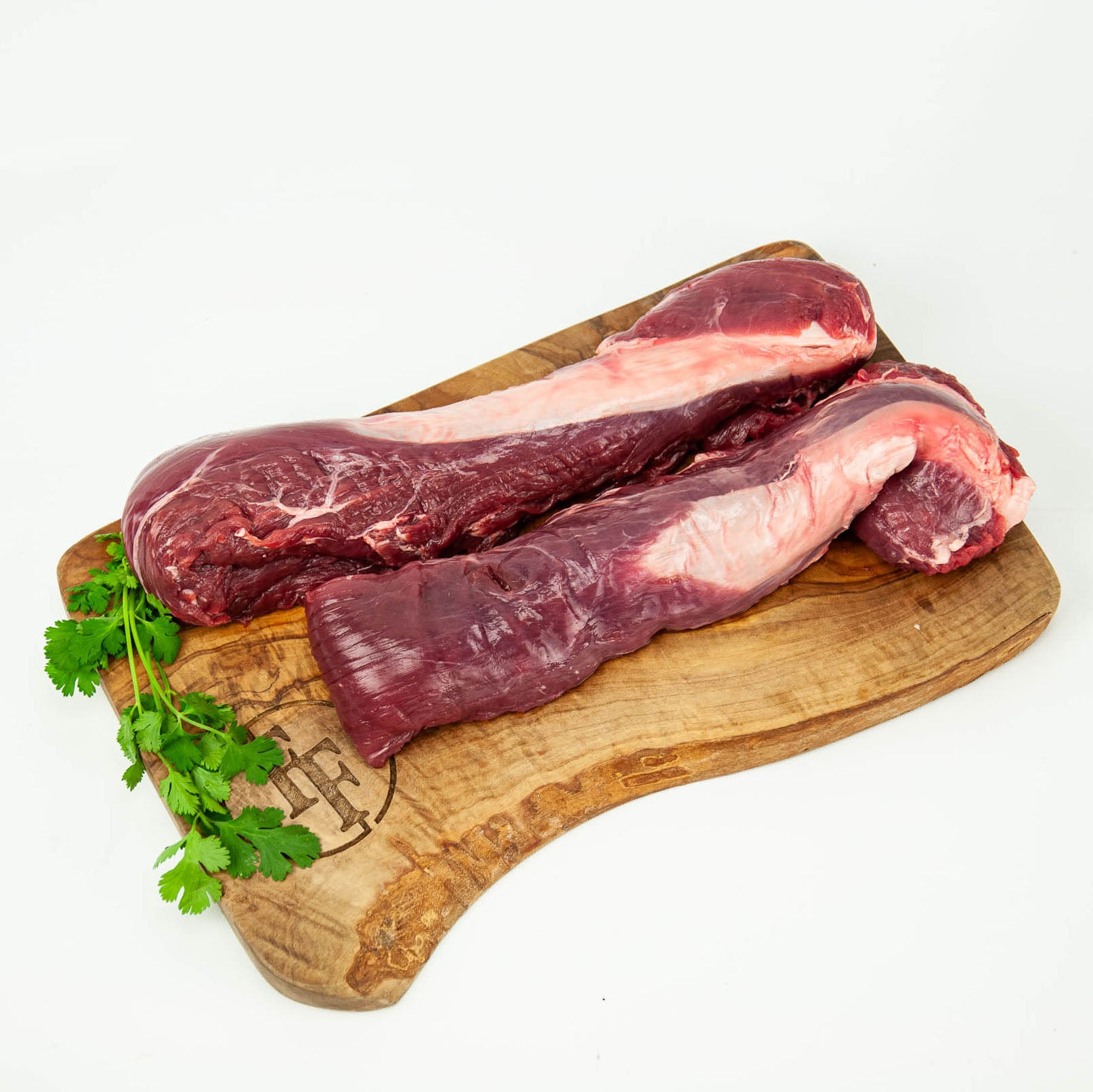 Raw meat on a wooden cutting board with herbs on a white background