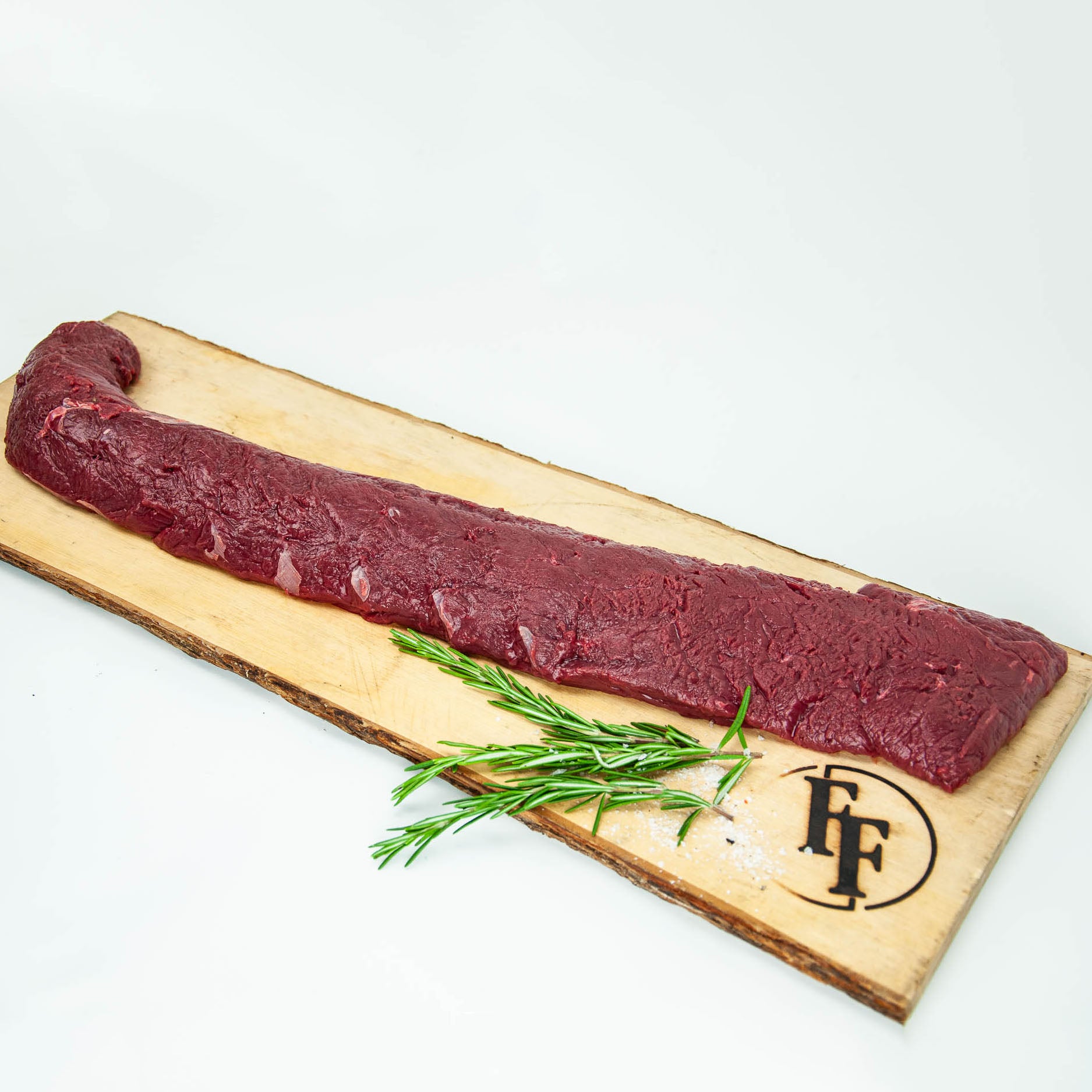 Raw meat on a wooden board with rosemary and a brand logo on a white background