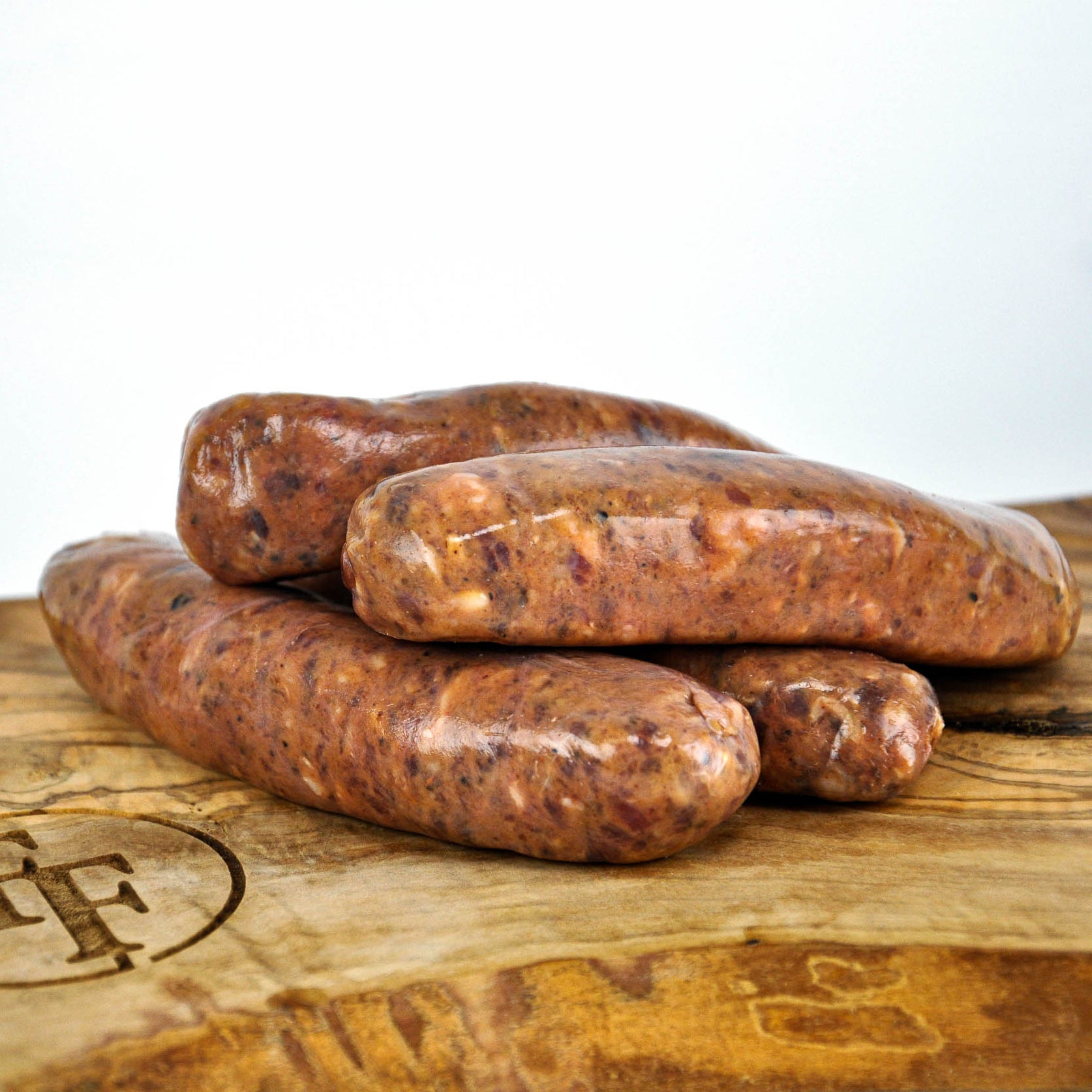 Three raw sausages on a wooden surface with a white background