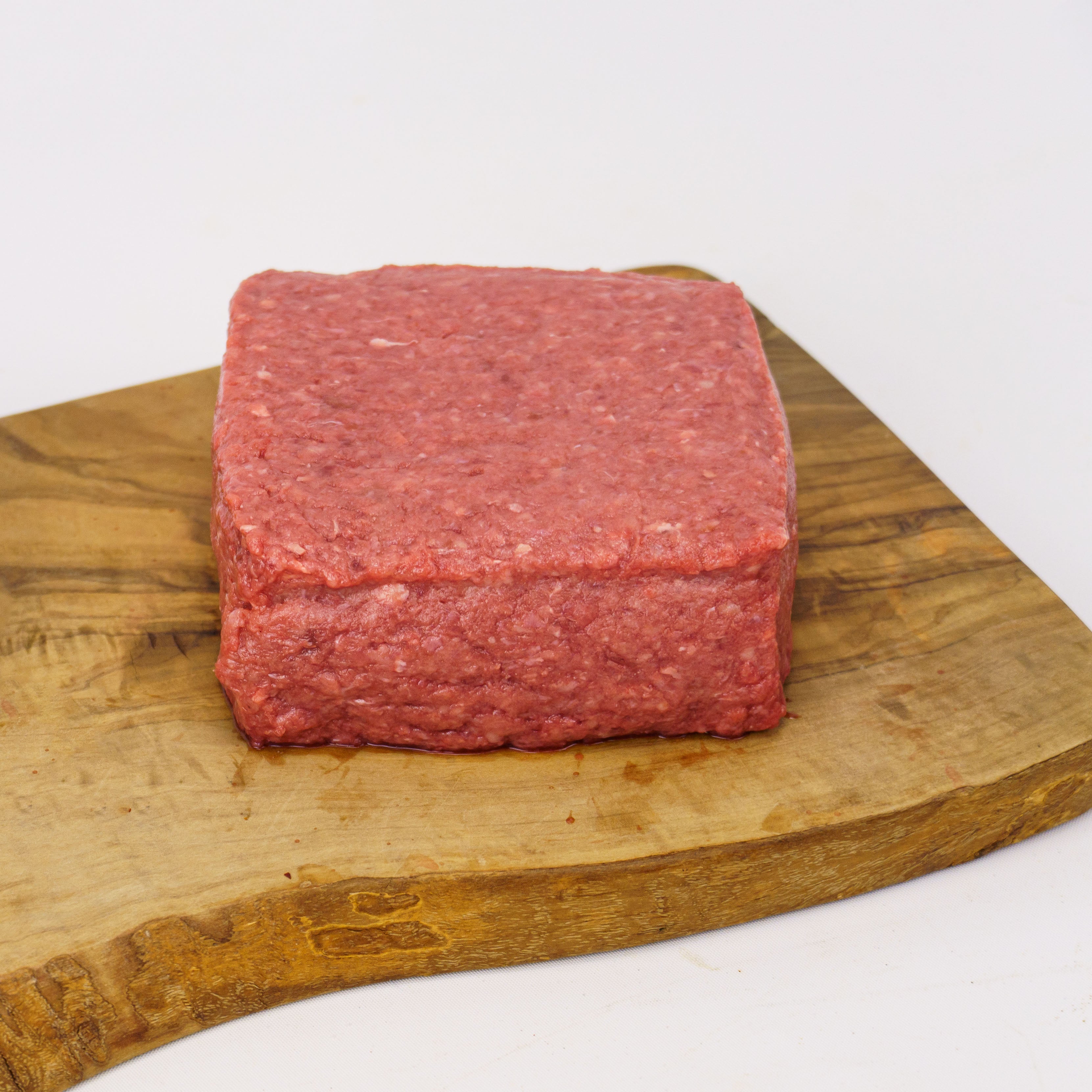 Block of ground meat on a wooden cutting board with a white background