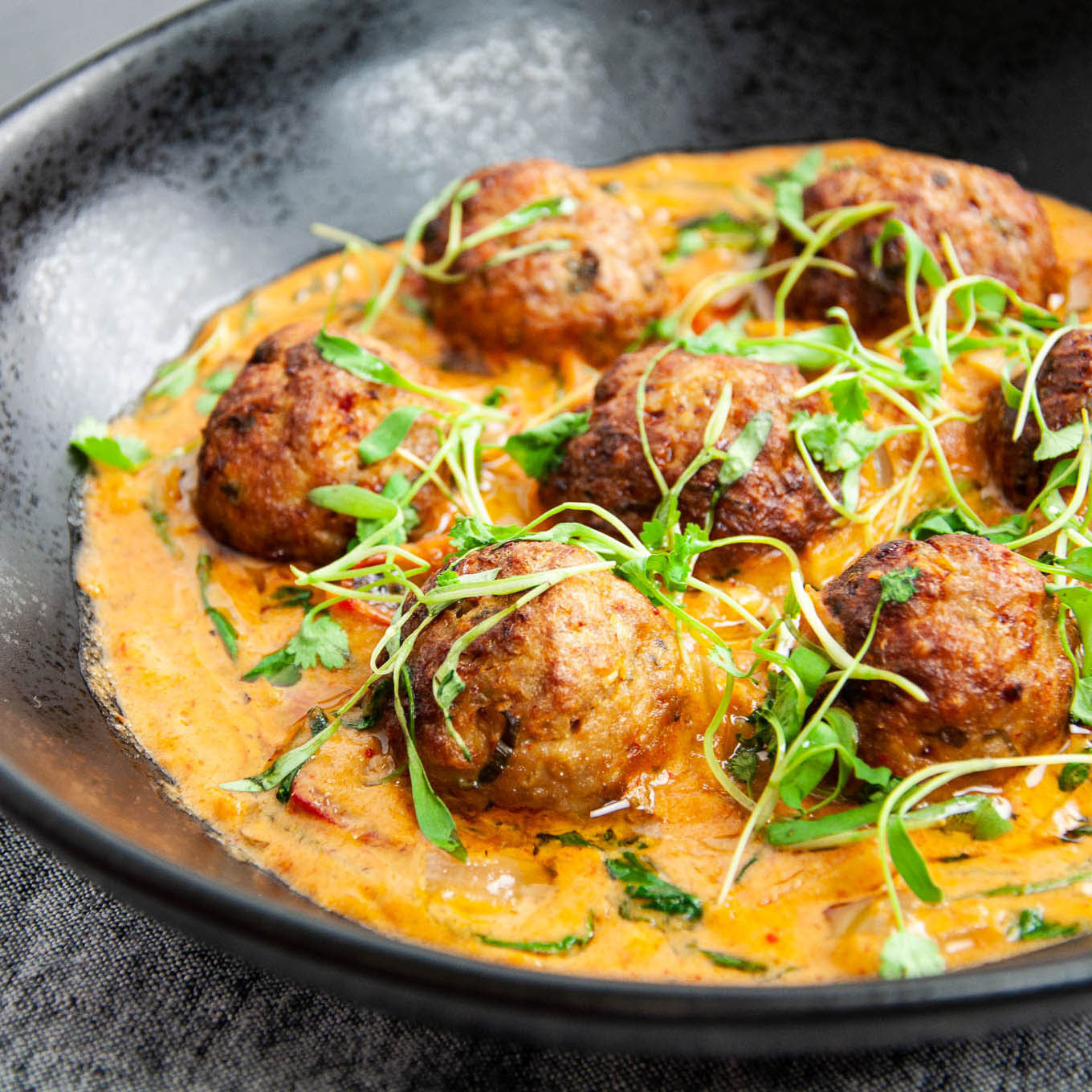 Dish with meatballs and creamy sauce on a dark plate