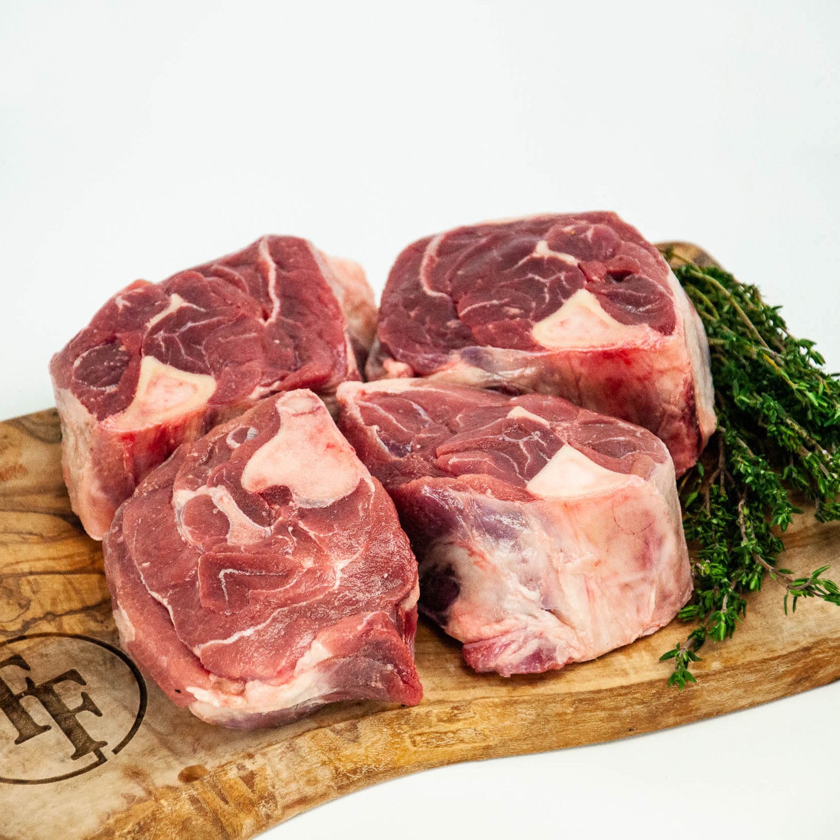 Raw beef chunks on a wooden board with herbs