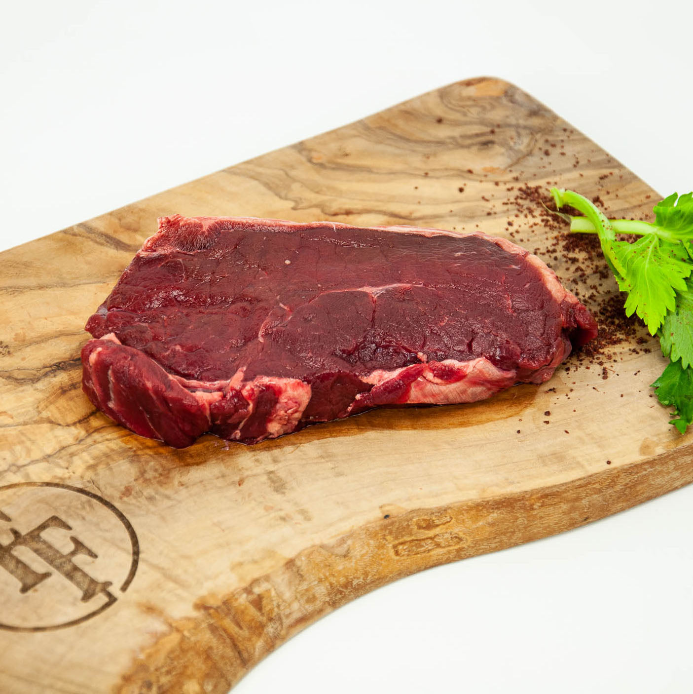 Raw steak on a wooden cutting board with a brand logo, on a white background