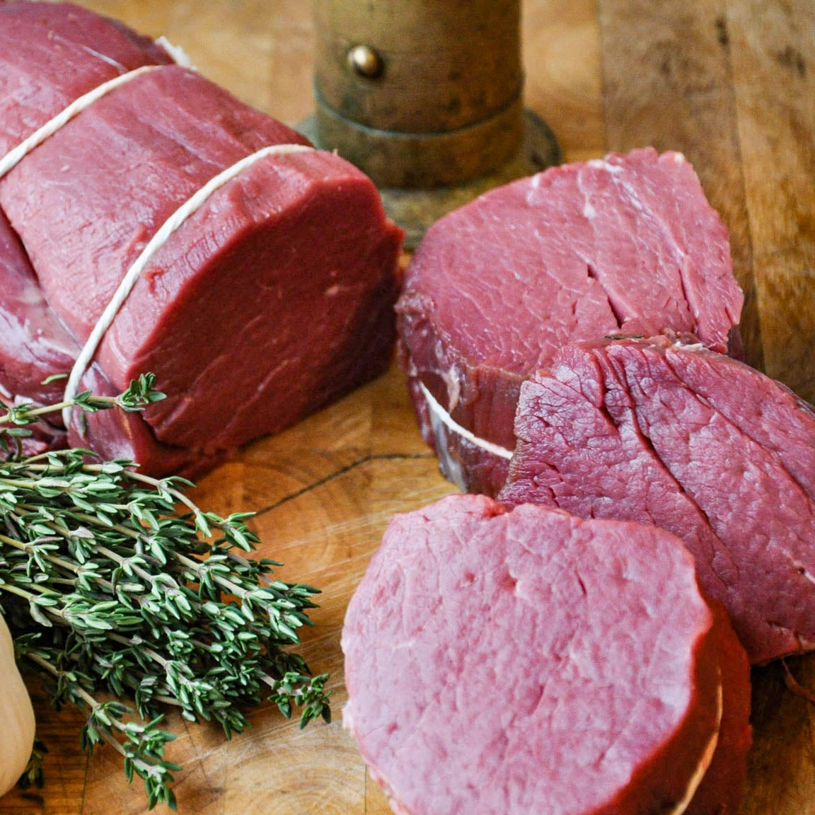 Raw bison with a thyme sprig on a wooden surface