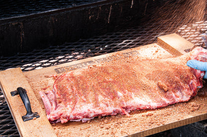 Raw ribs on a wooden cutting board over a grill