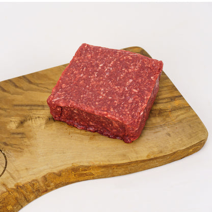 Raw ground beef on a wooden cutting board with a white background