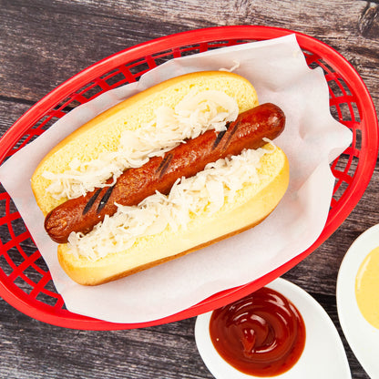 Hot dog with sauerkraut in a red basket on a wooden surface with ketchup on the side.