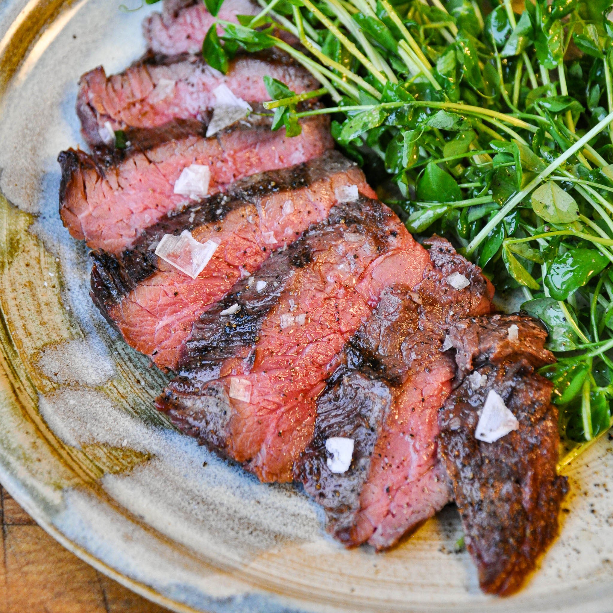 Sliced steak with green salad on a textured plate