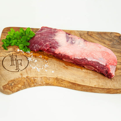 Raw meat on a wooden cutting board with herbs and salt, branded 'FF'.
