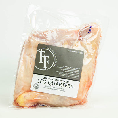 Packaged chicken leg quarters with Fossil Farms label on a white background