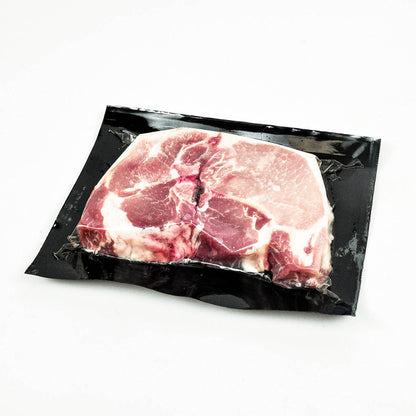 Raw pork chop in a black packaging on a white background