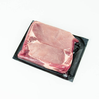 Raw pork chop in a black plastic packaging on a white background
