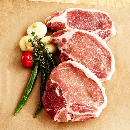 Raw pork chops with vegetables on a brown paper background