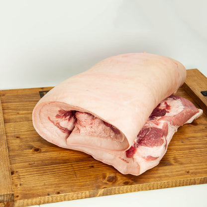 Raw pork belly on a wooden cutting board with a white background