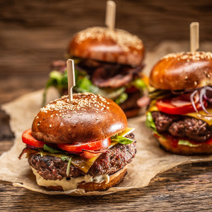 Three delicious-looking burgers on a wooden surface with a rustic background