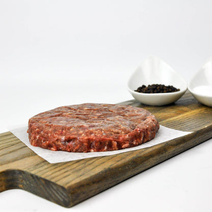 Raw ground meat on a wooden cutting board with a white background