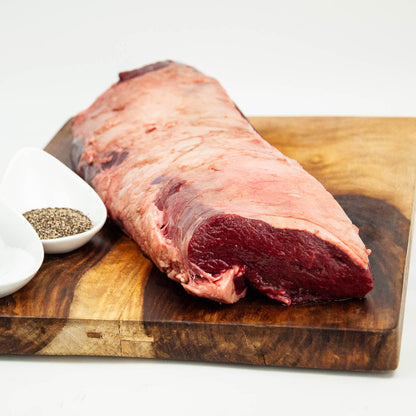 Raw beef brisket on a wooden cutting board with a white background