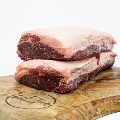Two pieces of raw meat on a wooden cutting board with a white background
