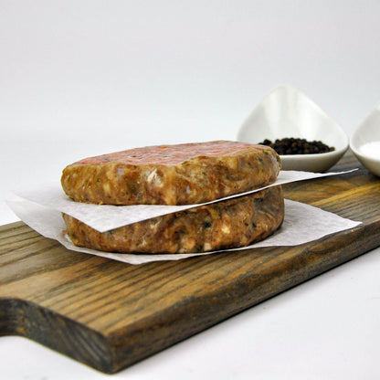 Two stacked meatloaf patties on a wooden cutting board with a white background