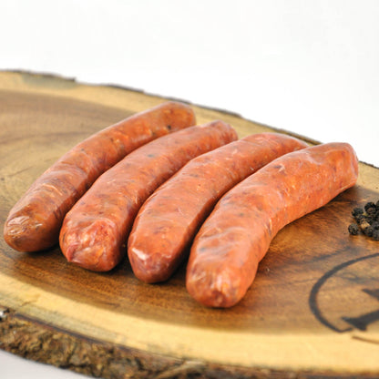 Four raw sausages on a wooden cutting board with a blurred background