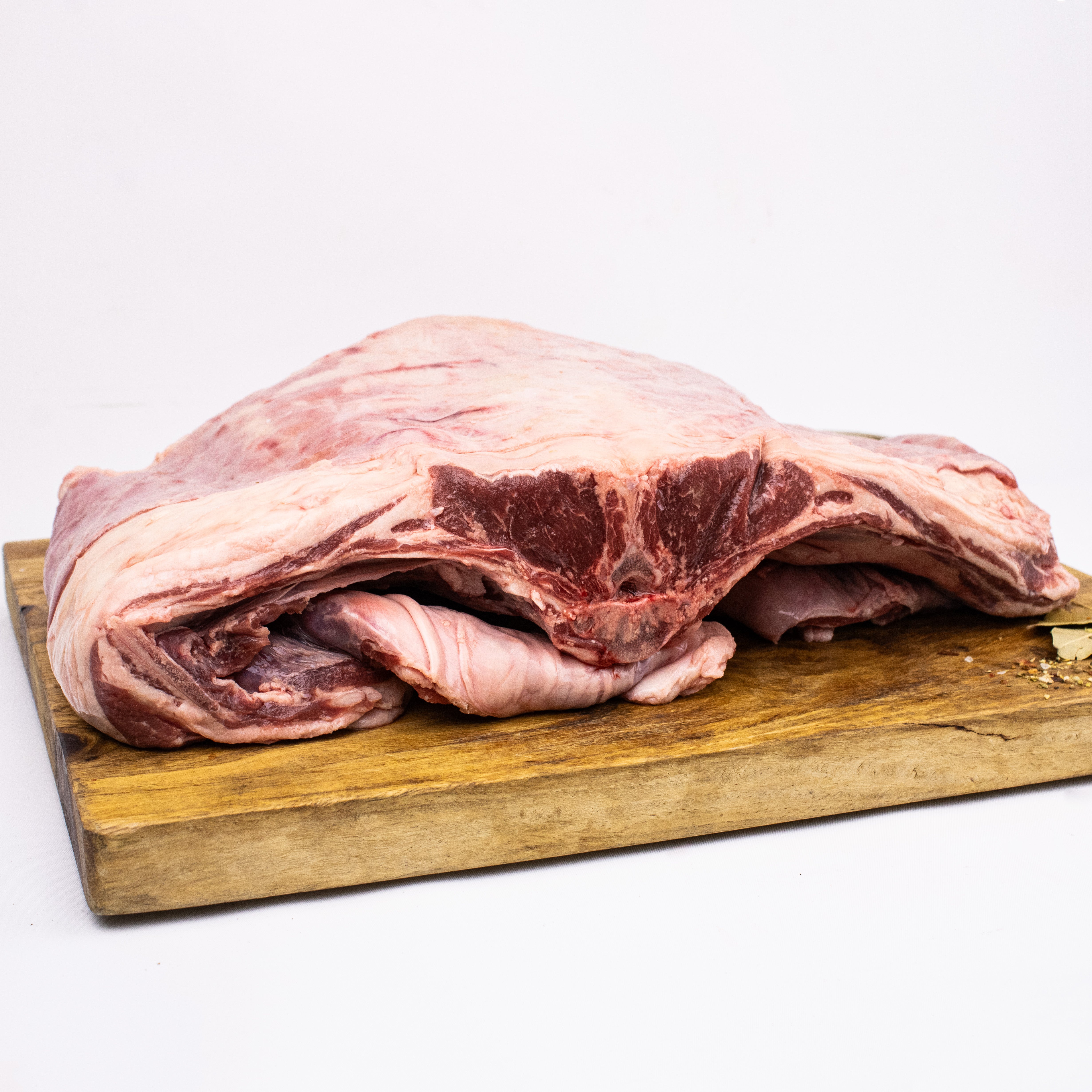 Raw pork shoulder on a wooden cutting board with a white background
