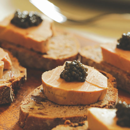 Toast with foie gras and caviar on a wooden board