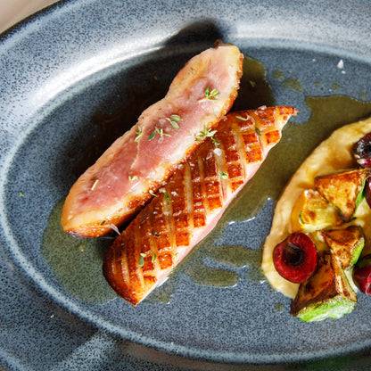 Sliced cooked meat with a side of vegetables on a gray plate